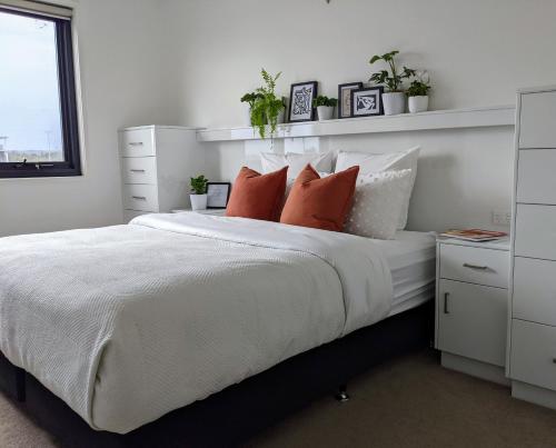 a bedroom with a white bed with pillows and plants at The Botanical 304 in Albury