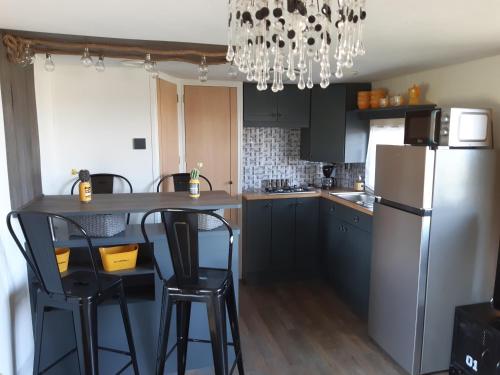 La cuisine est équipée d'un réfrigérateur et de deux tabourets de bar. dans l'établissement LE FER A CHEVAL, à Les Bizots