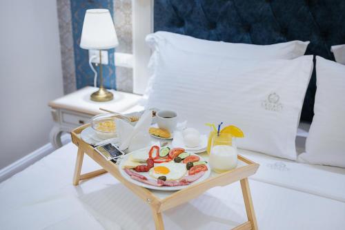 a tray of breakfast food on a table in a bedroom at Legacy Boutique Hotel in Korçë