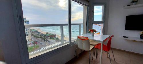 a room with a table and a view of the ocean at Hotel Apartment TLV-bat yam 81 in Bat Yam