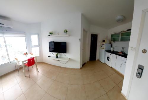 a kitchen with a table and a tv on a wall at Hotel Apartment TLV-bat yam 81 in Bat Yam