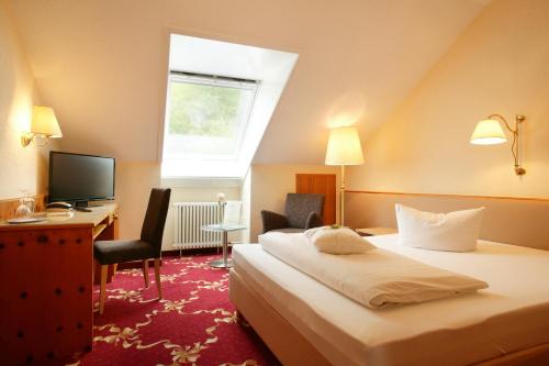 Habitación de hotel con cama, escritorio y TV. en Hotel Ochsen, en Höfen an der Enz