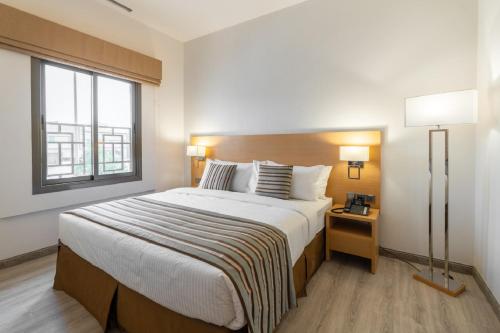 a bedroom with a large bed and a window at Aram Hotel - AlMeshael Exit 18 in Riyadh
