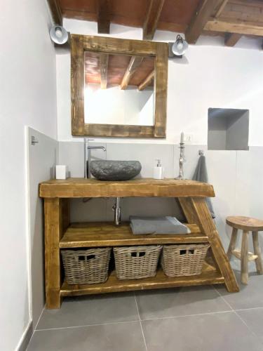 a bathroom with a wooden shelf with a sink and baskets at Il Falco - Rustico-Villa mit privatem Pool in Alleinlage in Caldana