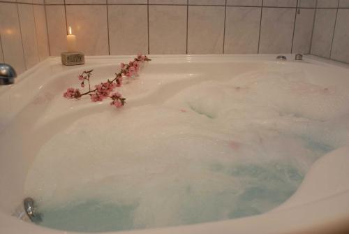 eine Badewanne mit rosa Blumen und einer Kerze in der Unterkunft Ferienwohnung Pferdezentrum Edersee in Waldeck