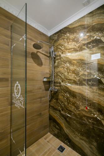 a shower in a bathroom with a stone wall at Legacy Boutique Hotel in Korçë