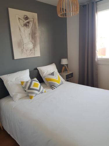 une chambre avec un grand lit blanc avec deux oreillers dans l'établissement Appartement à 5 minutes à pied du centre équestre du Sichon, à Vichy