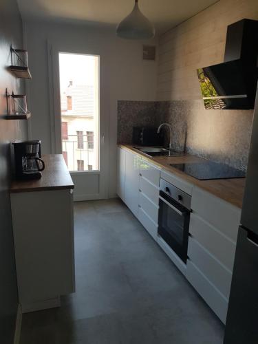 a kitchen with white cabinets and a sink and a window at Appartement à 5 minutes à pied du centre équestre du Sichon in Vichy