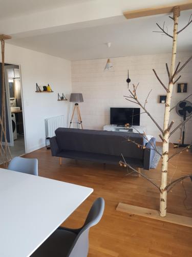un salon avec un canapé et un arbre dans l'établissement Appartement à 5 minutes à pied du centre équestre du Sichon, à Vichy