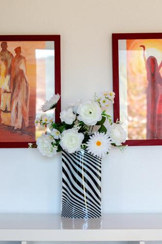 a vase filled with white flowers on a shelf with pictures at Dimitra Beach Apartments - Thassos Skala Potamias in Skala Potamias