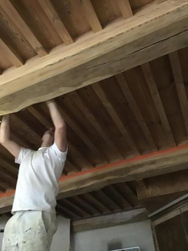 a man is working on a wooden ceiling at La Mazille , cossy vakantiestudio met zwembad in zuid-Bourgogne in Anglure-sous-Dun