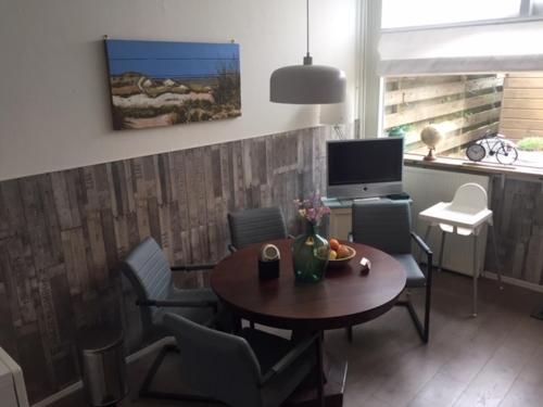 ein Wohnzimmer mit einem Tisch, Stühlen und einem TV in der Unterkunft B&B Kogervennetje in De Koog