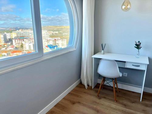 a desk and a chair in a room with a window at T2 com uma vista deslumbrante sobre o Atlântico! in Costa da Caparica