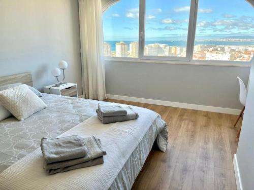 1 dormitorio con cama y ventana grande en T2 com uma vista deslumbrante sobre o Atlântico! en Costa da Caparica