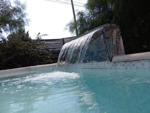 a pool with a water fountain in a swimming pool at Casa Magnolias in Tandil