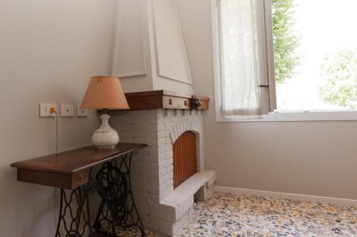 a room with a brick fireplace with a lamp on a table at la Brunita in Rubiera