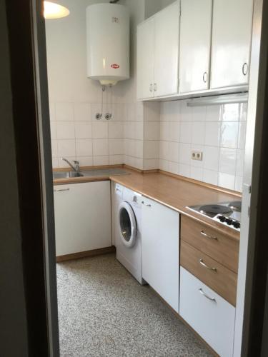 a kitchen with white cabinets and a washing machine at Hotel Adria in Bolzano