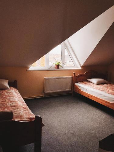 a attic bedroom with two beds and a window at Strenči Guesthouse in Strenči