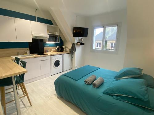a bedroom with a blue bed and a kitchen at Studio Confort Lorient Rue Vauban Hypercentre in Lorient