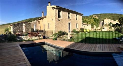 a house with a swimming pool in front of a house at Gîte Coquelicots in Montsalier