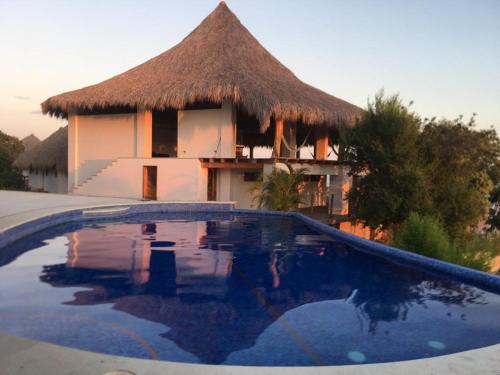 聖奧古斯提尼奧的住宿－Zazil Retreat，茅草屋顶和游泳池的房子