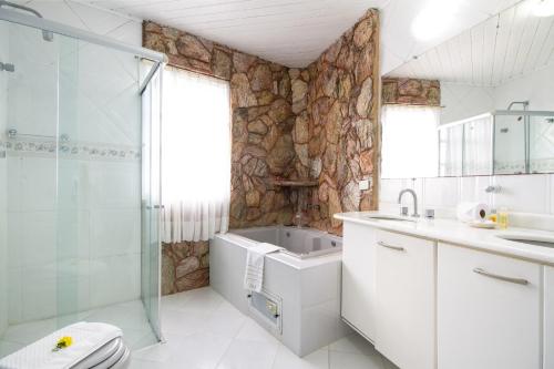 a bathroom with a sink, toilet and bathtub at Pousada Confraria da Terra in Campos do Jordão