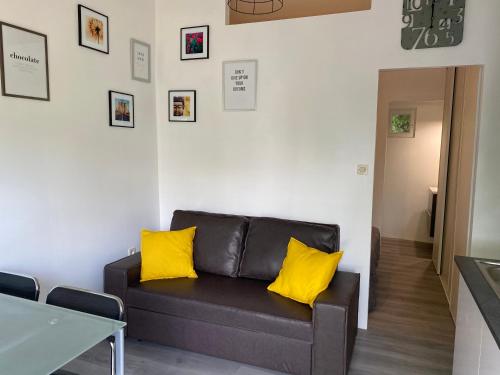 een woonkamer met een bank met gele kussens bij Jm Vacances Serignan Studio in Sérignan