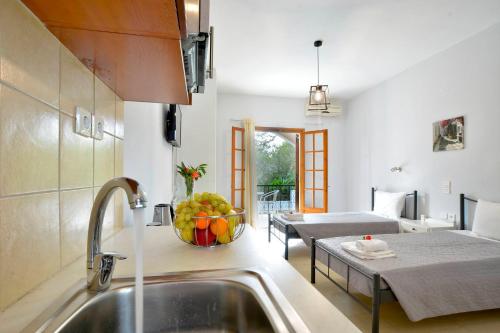 a kitchen with a sink and a bowl of fruit on the counter at Kalliopi Apartments in Roda