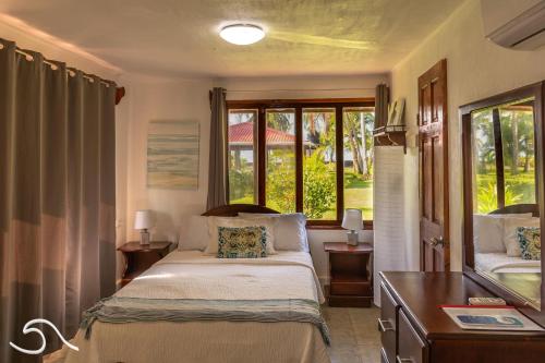 a bedroom with a bed and a desk and windows at Tranquilidad Resort in Parrita