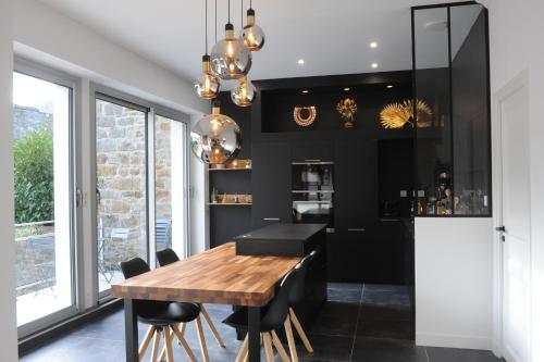 ein Esszimmer mit einem Holztisch und schwarzen Wänden in der Unterkunft Les Briochines - Cocon cosy en plein centre-ville in Saint-Brieuc