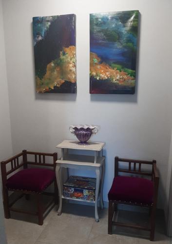 two chairs and a table with two paintings on the wall at Villa Rocco Country House in Ozzano Monferrato