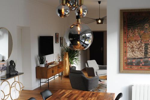 ein Wohnzimmer mit einem Tisch und einem Kronleuchter in der Unterkunft Les Briochines - Cocon cosy en plein centre-ville in Saint-Brieuc