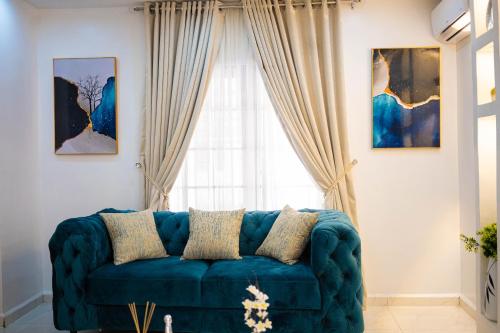 a blue couch in a living room with a window at Morak Homes - Luxury 4 bed home with PS5, 24hrs electricity, Super fast Wifi, Snooker, Games room - in a secured estate in Abuja