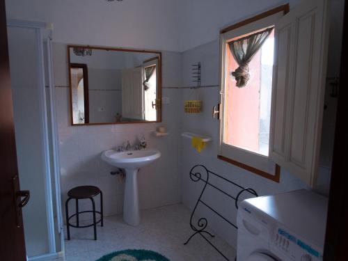 Baño blanco con lavabo y espejo en Pantelleria Serraglia, en Pantelleria