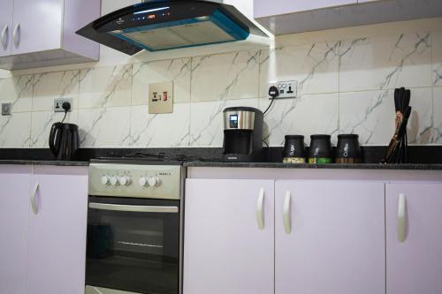 a kitchen with white cabinets and a stove at Morak Homes - Luxury 4 bed home with PS5, 24hrs electricity, Super fast Wifi, Snooker, Games room - in a secured estate in Abuja