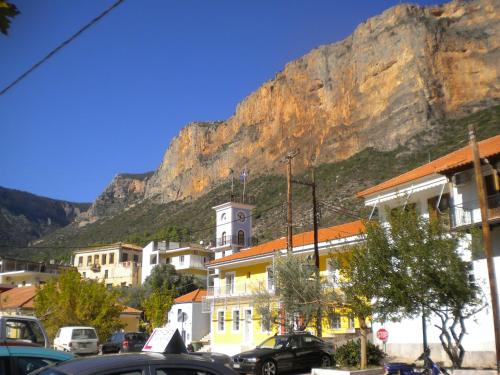 a building with a clock tower in front of a mountain at Amygdalia, a Stone House in a quiet landscape in Leonidion