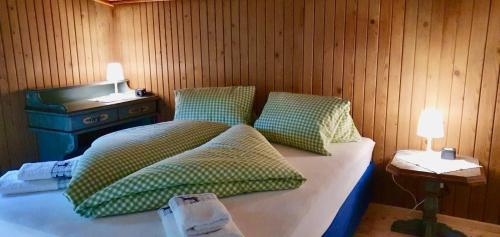 a bed with green pillows in a wooden room at Alpen-Chalets Achensee in Maurach