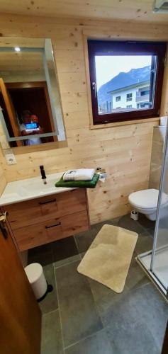 a bathroom with a sink and a toilet and a window at Alpen-Chalets Achensee in Maurach