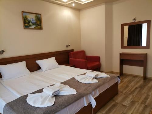 a hotel room with a bed and a red chair at HOTEL PARIS Relax Zone in Balchik