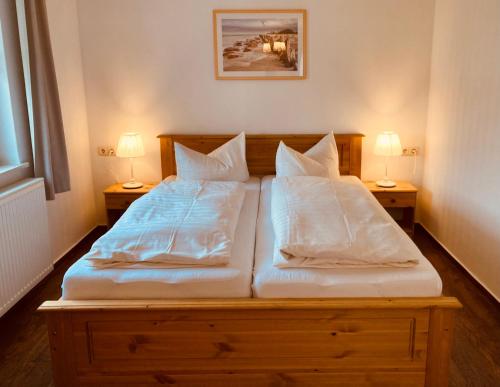 a bed with two pillows on it with two lamps at Strandkojen in Trassenheide
