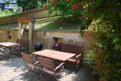 a wooden table and chairs and a stone wall at FH Am Osterbrunnen in Hinterhermsdorf