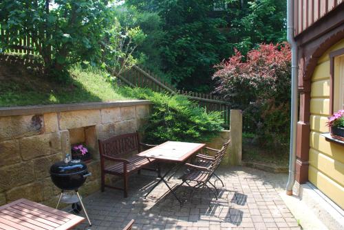 a patio with a table and chairs next to a wall at FH Am Osterbrunnen in Hinterhermsdorf