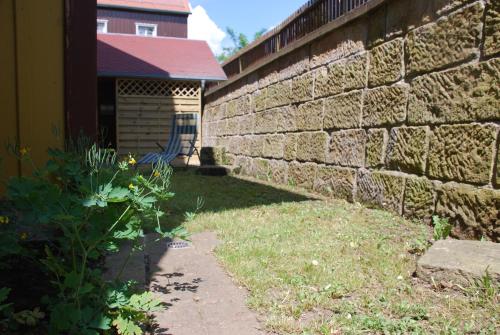 a brick wall next to a yard with a building at FH Am Osterbrunnen in Hinterhermsdorf