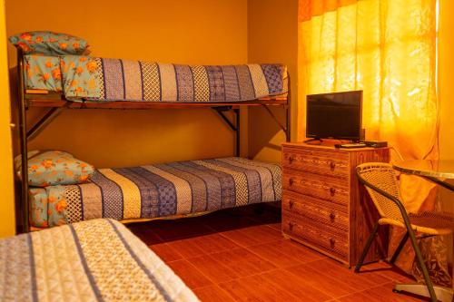 a bedroom with bunk beds and a desk with a television at La Casa del Sol Naciente in San Pedro de Atacama