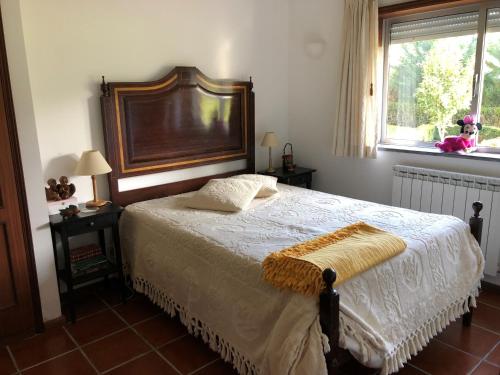 een slaapkamer met een bed met een houten hoofdeinde en een raam bij Quinta das Oliveiras in Moimenta da Serra