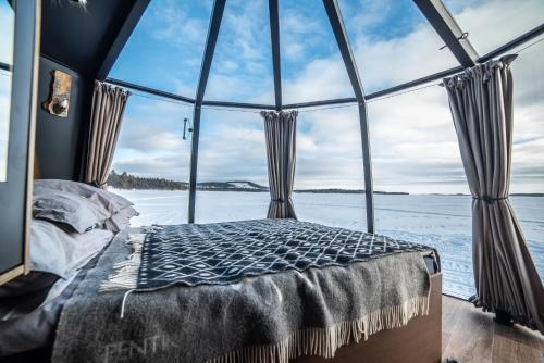 Bett in einem Zimmer mit einem großen Fenster in der Unterkunft Northern Lights Glass Igloo Getaway For Couples in Rovaniemi