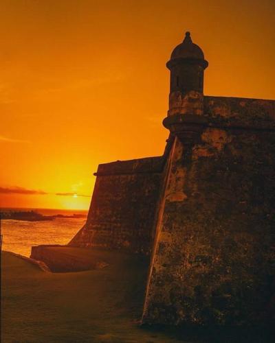 a sunset over the ocean with a lighthouse on a wall at Gavidias Guest House in San Lorenzo