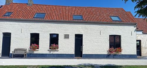 a white building with two windows and a bench at Hoeve Korenzegen. Oase van rust dichtbij strand in De Haan