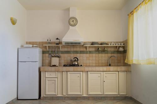 a kitchen with a white refrigerator and a clock on the wall at Lovely beach front apartment in Santa Maria in Santa Maria