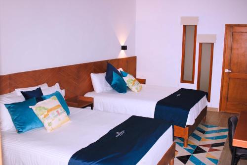 two beds in a room with blue and white at HOTEL CHURUMUCO in San José Iturbide